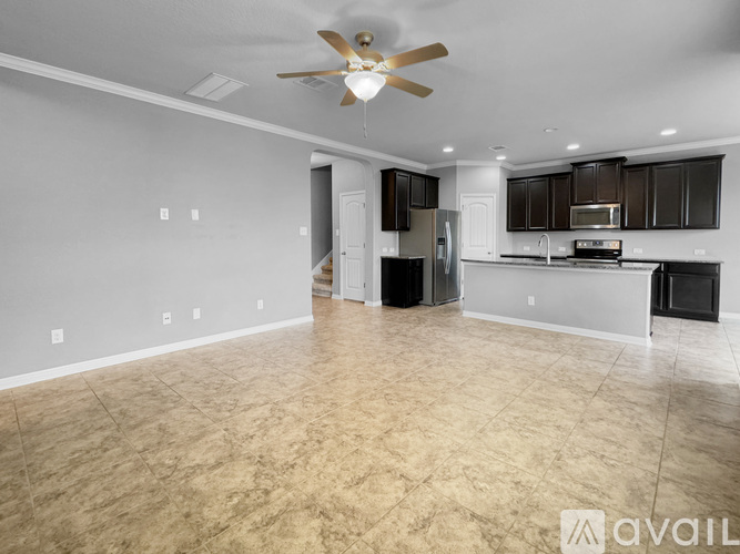 A spacious kitchen and living room with a ceiling fan and lighting fixtures.