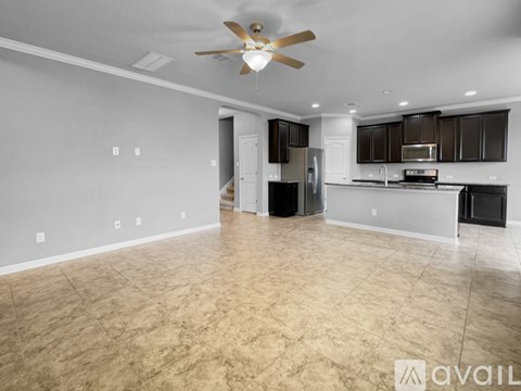 A spacious kitchen and living room with a ceiling fan and lighting fixtures.