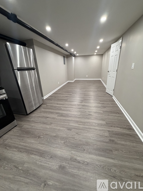 A spacious room with a grey floor and a white door at the end.