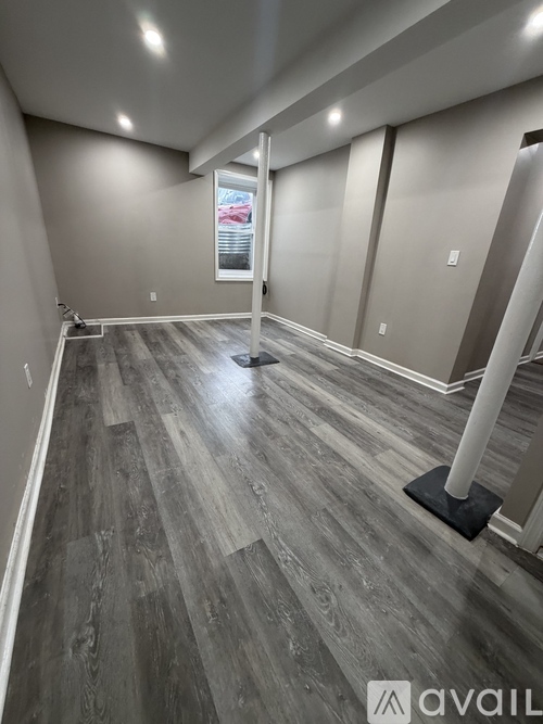 A room with grey wooden flooring and a window.