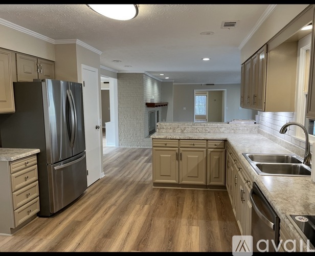 A kitchen with wooden floors and a stainless steel refrigerator.