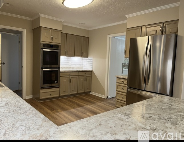 A kitchen with a refrigerator, oven, and cabinets.