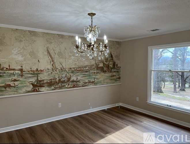 A room with a large painting of boats on the wall and a chandelier hanging from the ceiling.