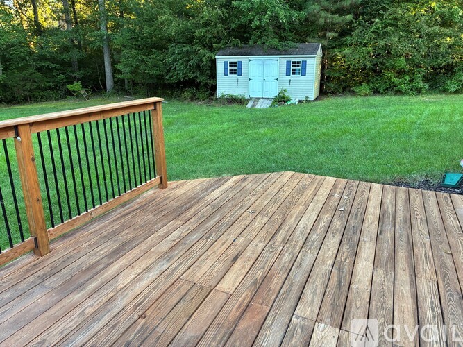 A wooden deck with a railing and a shed in the background.