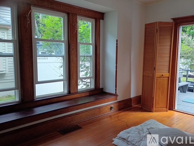 A room with wooden floors and a large window with a view of a tree.