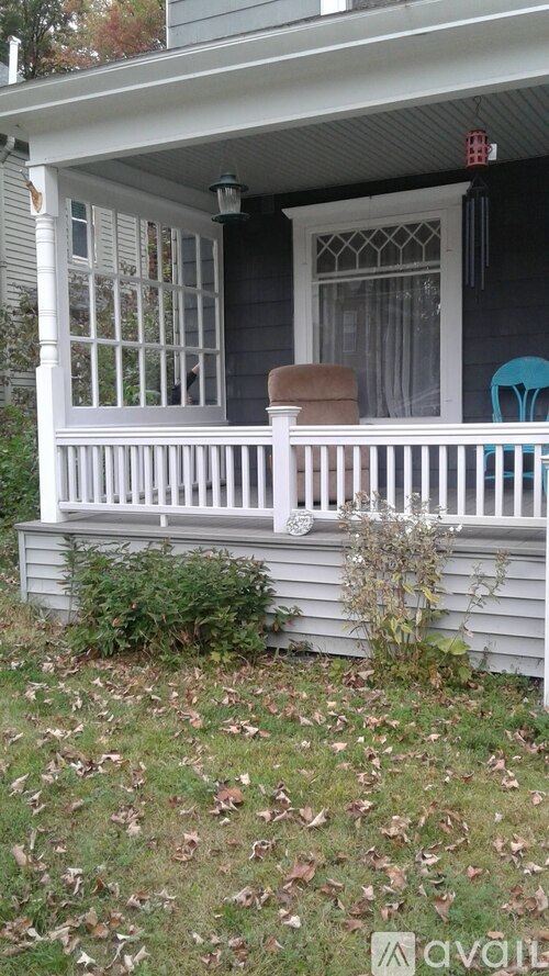 A porch with a white railing and a brown chair.