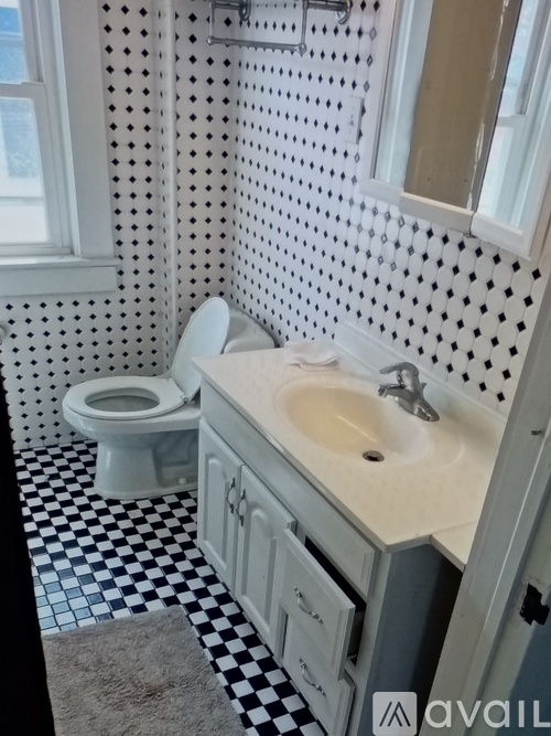 A white toilet is in a bathroom with a black and white checkered floor.