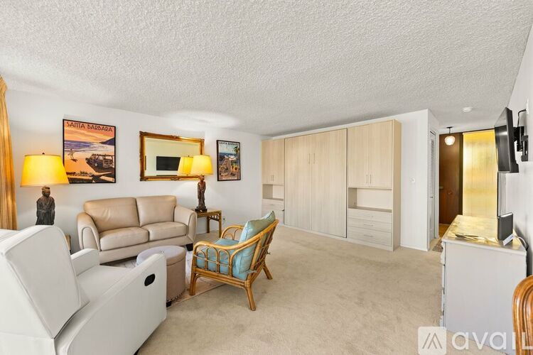 A living room with a white couch, a wooden chair, and a television.