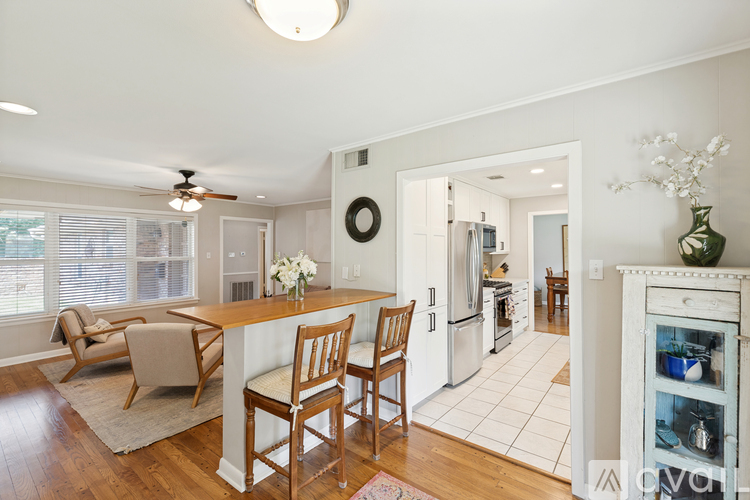 A kitchen with a table and chairs in the foreground and a refrigerator in the background.