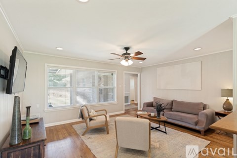 A living room with a grey couch, a wooden table, and a television on the wall.
