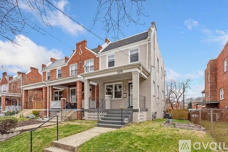 A two-story house with a front porch and a fence.