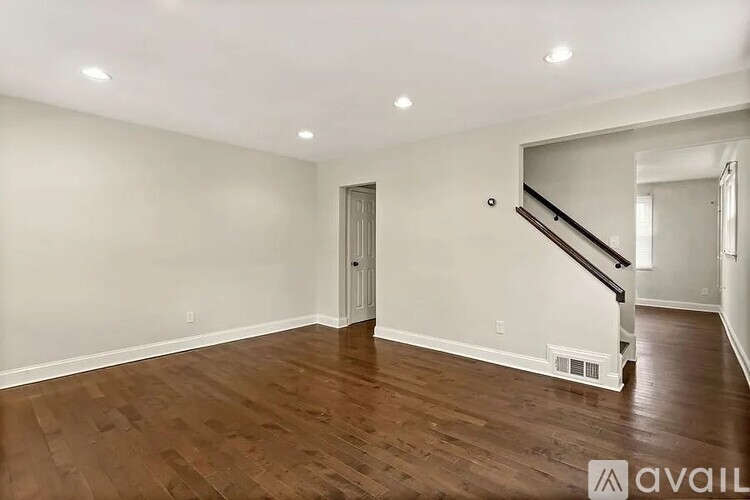 A spacious room with wooden flooring and a staircase.