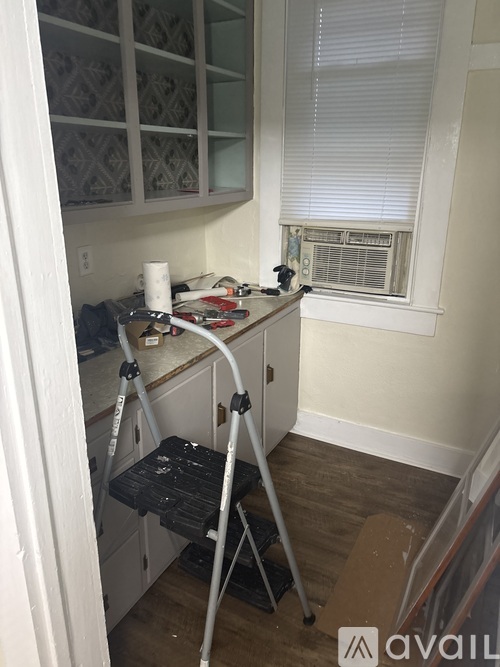 A kitchen with a white cabinet and a window with blinds.