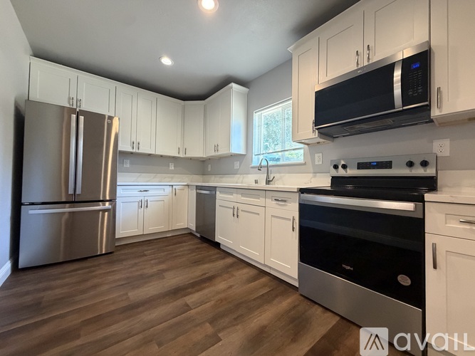 A kitchen with white cabinets and a stainless steel refrigerator.