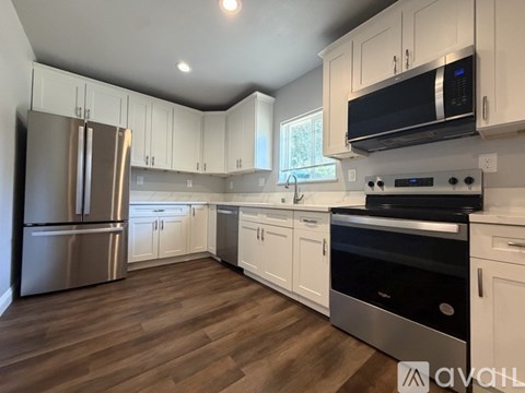 A kitchen with white cabinets and a stainless steel refrigerator.