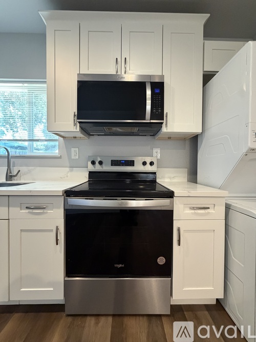 A modern kitchen with white cabinets and stainless steel appliances.