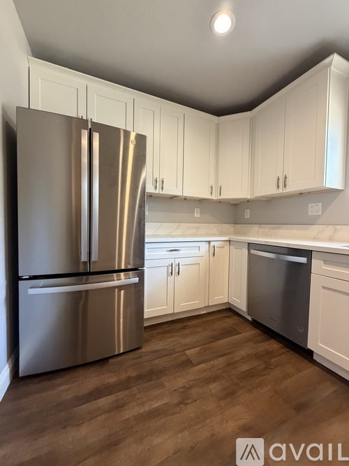 A kitchen with a stainless steel refrigerator and wooden flooring.
