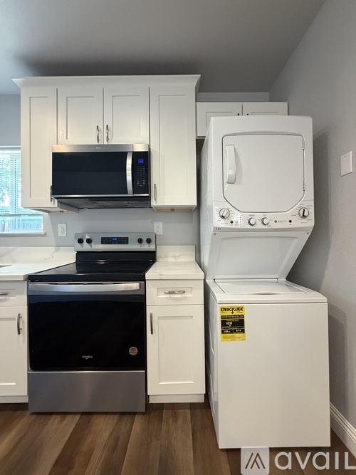 A kitchen with white cabinets and a black microwave above the stove.