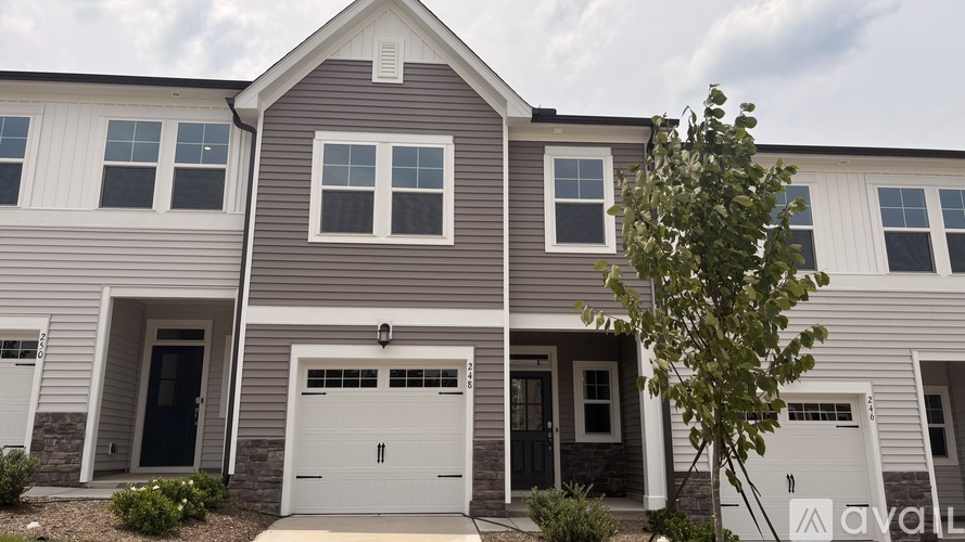 A two-story house with a garage and a tree in front.