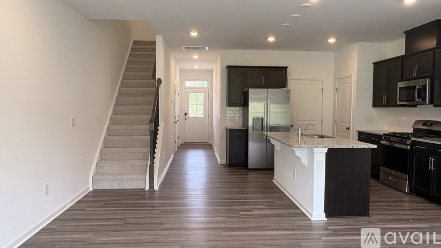 A spacious kitchen and living room with a staircase on the left side.