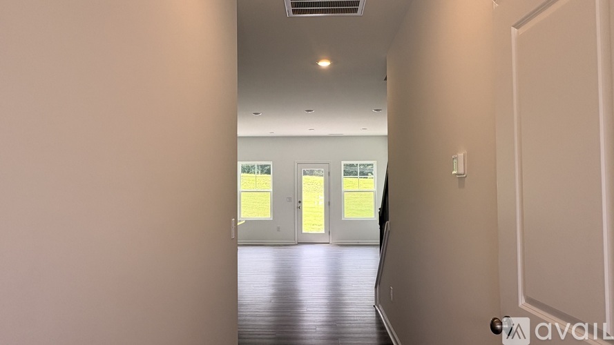 A hallway with a door on the right and two doors in the distance.