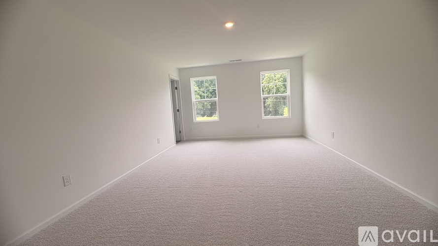 A room with a carpeted floor and a window with a view of trees.