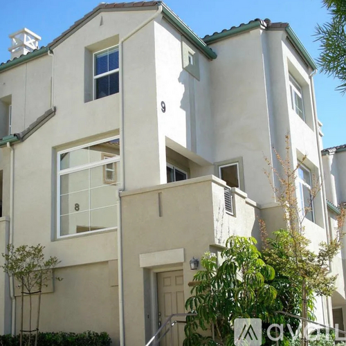 A white two story house with a balcony on the second floor.