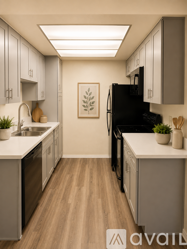 A kitchen with a black refrigerator and wooden floors.
