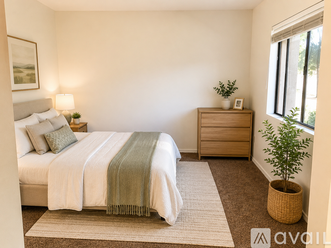 A bedroom with a bed, nightstand, and a plant.