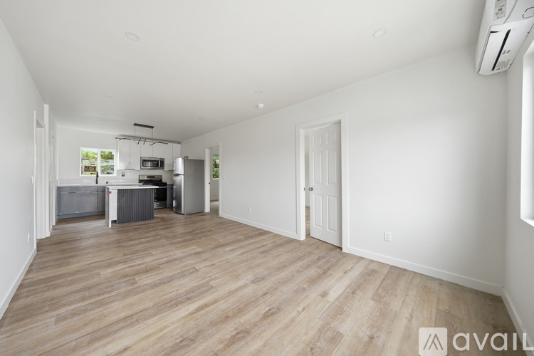 A spacious room with wooden flooring and white walls.