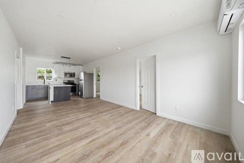 A spacious room with wooden flooring and white walls.