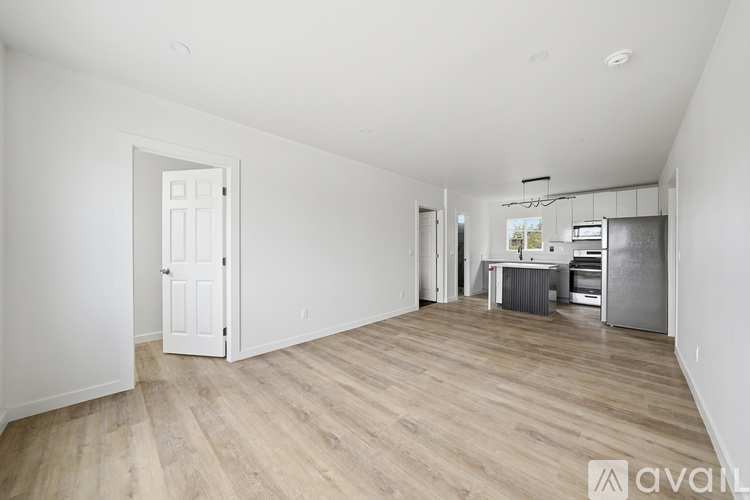 A spacious room with wooden flooring and a kitchenette in the background.