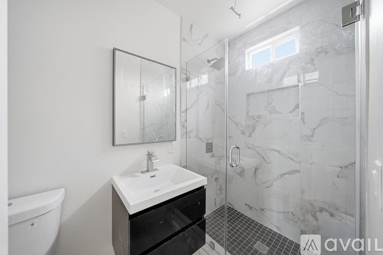 A bathroom with a sink, mirror, and shower.
