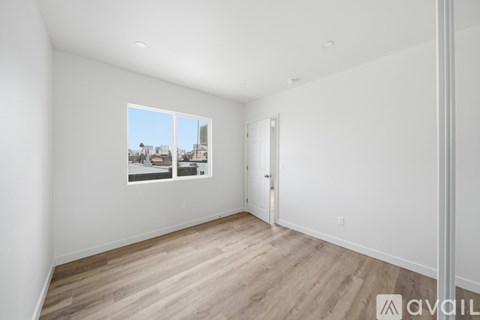 A room with a window showing a view of buildings outside.