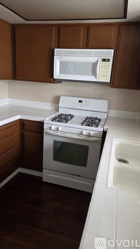 A kitchen with a white stove top oven and microwave above it.