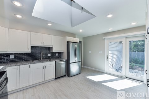 A modern kitchen with white cabinets and a black backsplash.