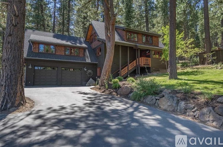 A house with a driveway in front of it surrounded by trees.