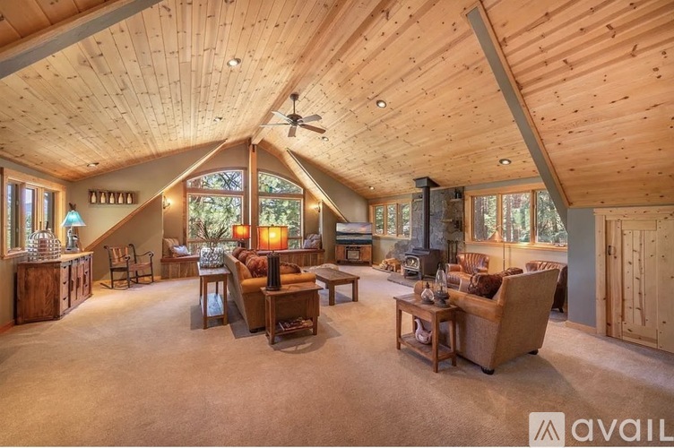 A spacious living room with wooden ceiling and furniture.