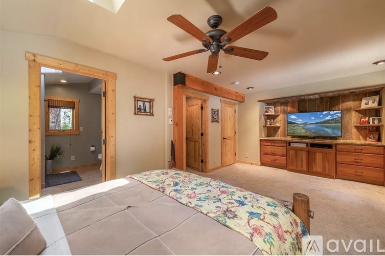 A bedroom with a large bed and a ceiling fan.