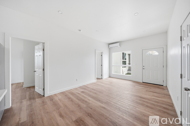 A spacious room with wooden flooring and white walls.