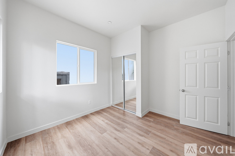 A room with a white door and a window with a view of a building outside.