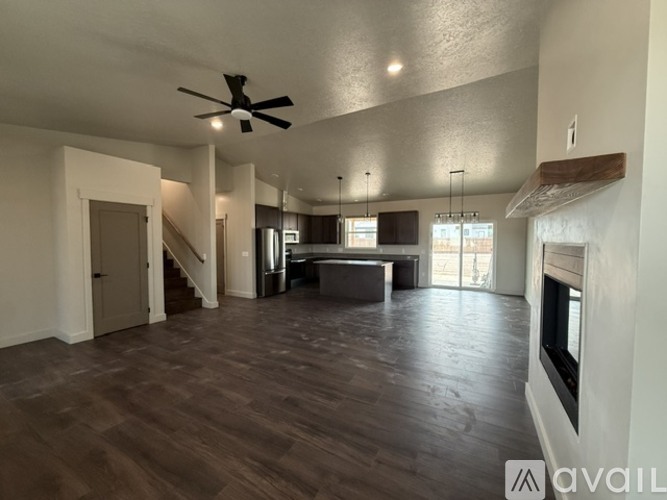 A spacious living room with a fireplace and a ceiling fan.
