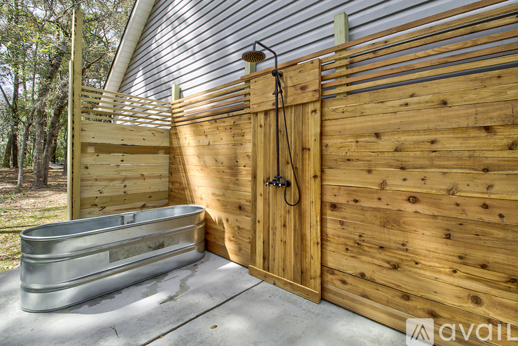A wooden shed with a metal tub in front of it.