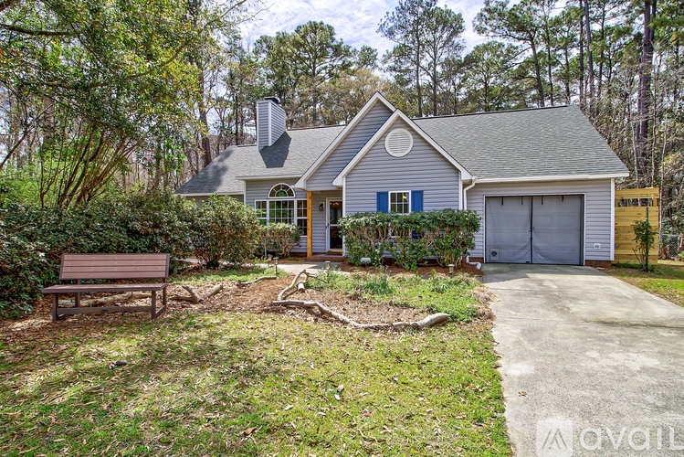 A house with a grey roof and a blue door is surrounded by trees.