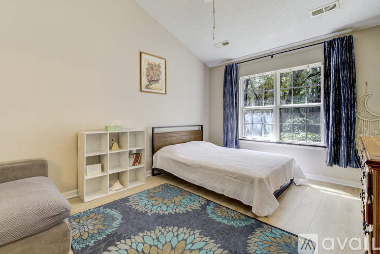 A bedroom with a bed, a window with curtains, and a bookshelf with books.