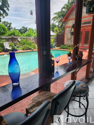 A blue vase sits on a table by a pool.