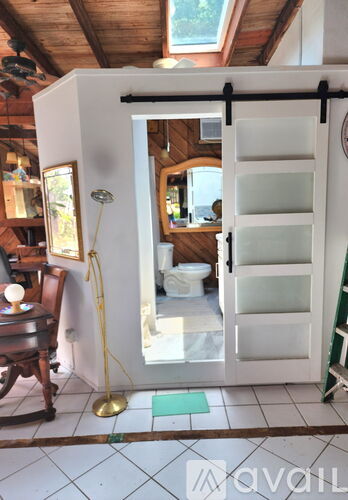 A room with a wooden ceiling and a white door leading to a bathroom.