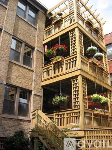 A tall wooden building with balconies and flower pots.
