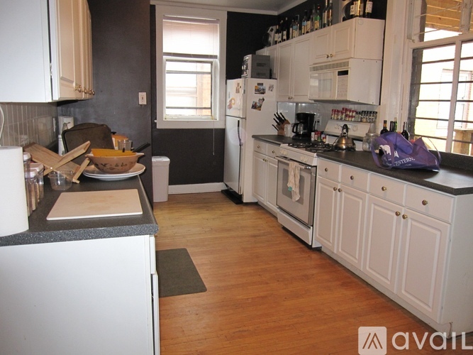 A kitchen with white cabinets and a black refrigerator.