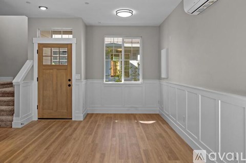 A room with a wooden floor and a window with a view of trees.